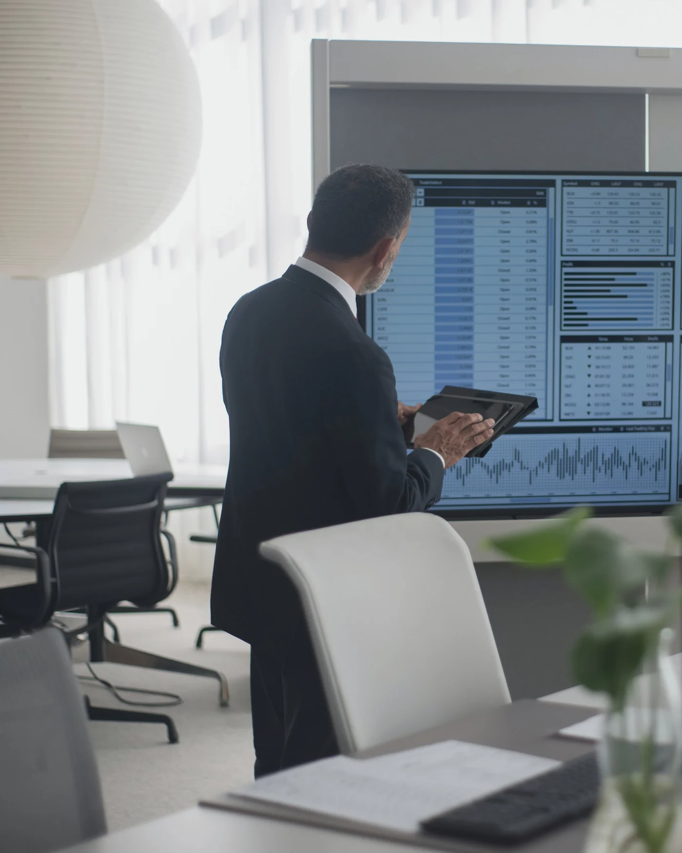 A professional before a wall of operational dashboards, seen from behind